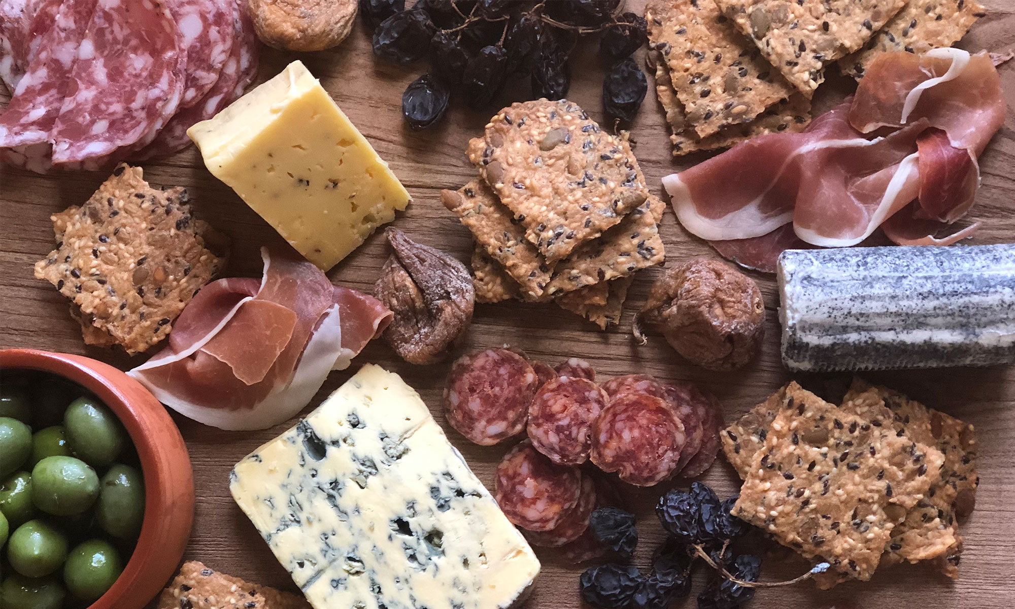 Wooden board with cheese, crackers, deli items